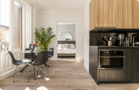 studio-apartment-with-open-kitchen-with-black-base-units-round-glass-dining-table-balcony